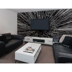 a living room filled with black furniture and a flat screen tv mounted to the wall