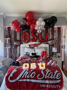 a bedroom decorated with balloons and decorations for an osu graduation party in red, white and black