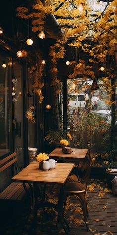 an outdoor dining area with wooden tables and chairs covered in yellow flowers, hanging from the ceiling