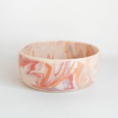 a white and pink marbled bowl sitting on top of a table