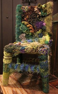 a chair made out of grass and flowers on top of a wooden floor next to a door