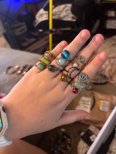 a woman's hand holding several rings with different designs on them, all in various shapes and sizes