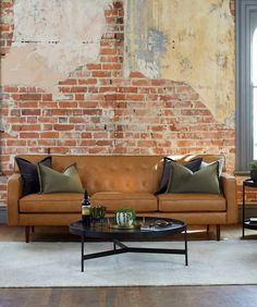 a living room filled with furniture and a brick wall behind the couch is a coffee table