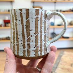 a hand holding a coffee mug with white and brown stripes