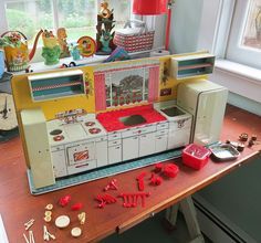 an old fashioned toy stove and oven on a wooden table in front of a window