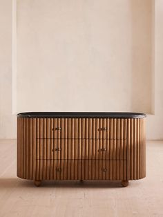 a wooden dresser with black top in an empty room