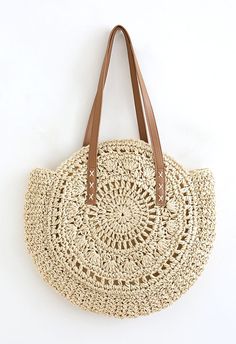 a straw bag with leather handles on the front and side, sitting on a white surface