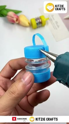 a person is holding a blue bottle with a pair of scissors in it and the other one has a plastic cap