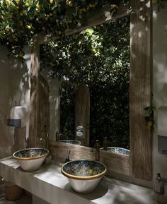 two bowls are sitting on a counter in front of a mirror that has lemons hanging from it