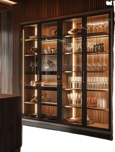 an illuminated display case with wine glasses and other items in the glass doored cabinet