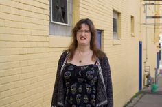 a woman standing in front of a yellow brick building