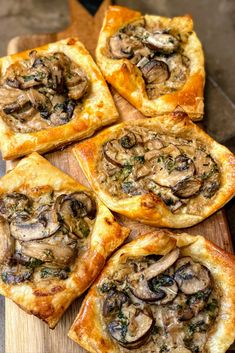 small pizzas with mushrooms on them sitting on a cutting board