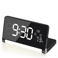 an alarm clock is displayed on a white surface with the time at 11 30 pm