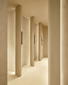 an empty hallway with white walls and light colored concrete columns on either side of the room