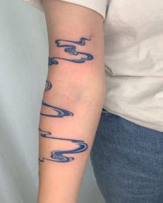 a woman with a tattoo on her arm that has waves coming out of the water