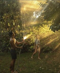 a man is spraying water on his dog in the yard while he plays with it