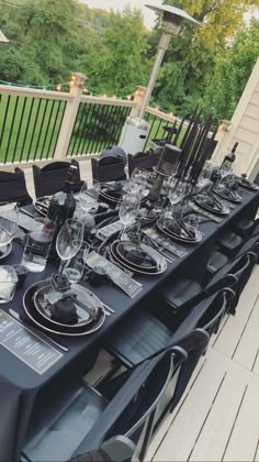 an outdoor dining table set up with black and white plates, silverware and place settings