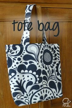 a black and white bag hanging from a wooden door with the words tote bag on it