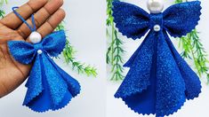 an ornament made out of blue paper with bows and pearls on it is being held