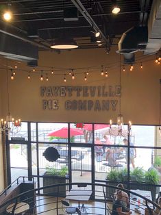 the inside of a restaurant with people sitting at tables and umbrellas hanging from the ceiling