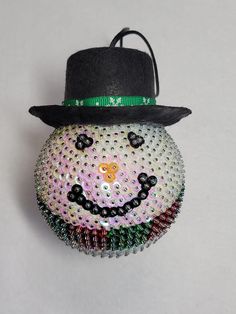 a beaded snowman ornament with a hat on it's head