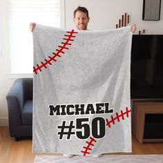 a man holding up a baseball towel with the number 50 on it