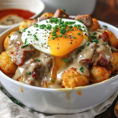 a bowl filled with tater tots covered in an egg and gravy