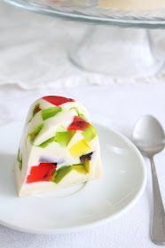 a piece of fruit cake on a plate with a spoon and glass bowl in the background