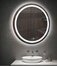 a white sink sitting under a round mirror