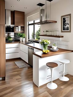 a modern kitchen with white cabinets and wood flooring is pictured in this image, there are two stools at the center of the island