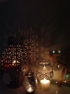 three lit candles sitting next to each other in front of a wall with shadows on it