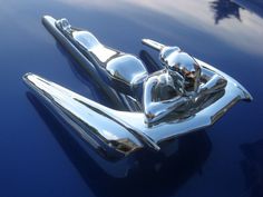 the hood ornament of an old car is reflected in the shiny chrome paint