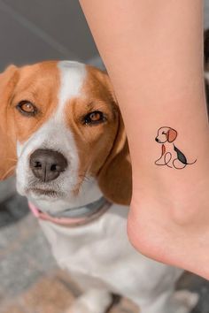 a small dog is sitting next to a woman's leg with a tattoo on it