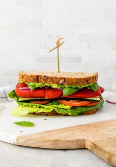 a large sandwich with lettuce, tomato and other vegetables on a cutting board