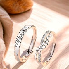 two wedding rings sitting on top of a wooden table next to an orange piece of bread