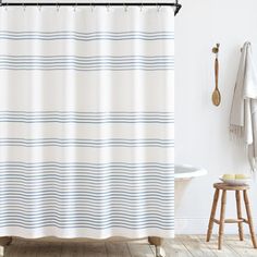 a white shower curtain with blue and gray stripes on it, next to a bathtub