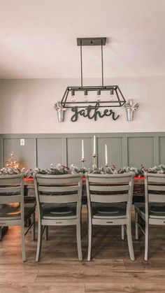 a dining room table set for six with candles and christmas decorations on the wall behind it