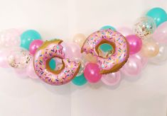 a doughnut with sprinkles and balloons hanging on a wall