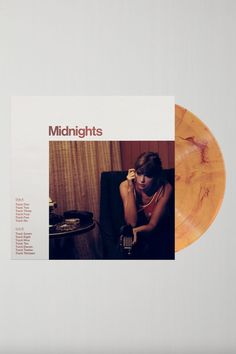 an orange vinyl record with the words midnights on it and a woman sitting in a chair