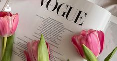 three pink tulips sitting on top of an open book with the word voge written in it