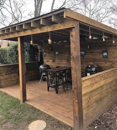 an outdoor bar made out of wood with stools on the top and tables under it