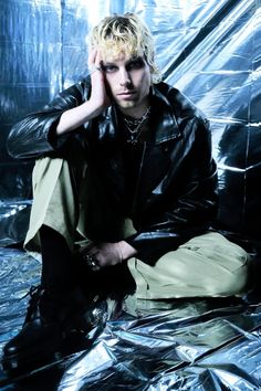 a young man sitting on top of a shiny metal sheeted floor with his hands to his head