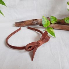 a brown leather headband with a bow on it and some green leaves in the background