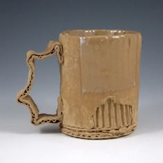 a brown ceramic mug with a chain on the handle is shown in front of a gray background