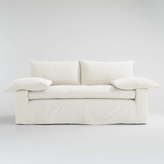 a white couch with two pillows on it's back and one arm folded up