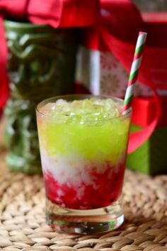 a colorful drink in a glass with a striped straw and green, red, and white substance