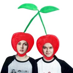 two people wearing matching hats with cherries on them, one is red and the other is green