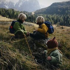 two children sitting on a rock in the mountains