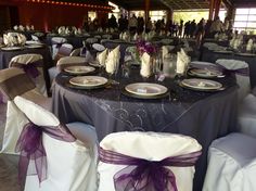 the tables are set up with purple sashes and silver plates for dinner guests to eat