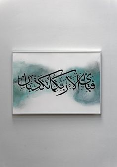 an arabic calligraphy is displayed on a white wall with blue and green watercolors